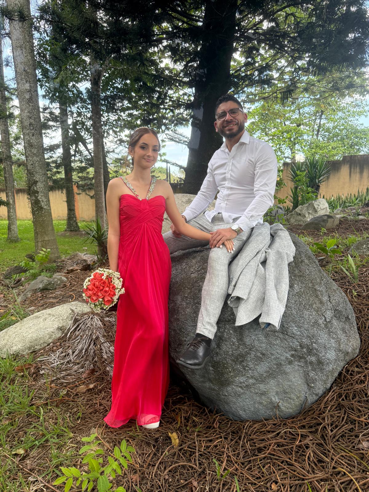 José Miguel y Amanda en un jardín, ella con vestido rojo